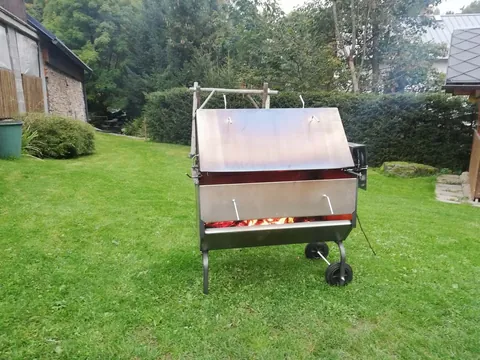Pojízdný gril s rožněm na trávníku u chalupy