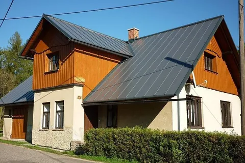 Dvoupatrová chalupa U Bigena s dřevěným obkladem a šedou střechou v letním slunci