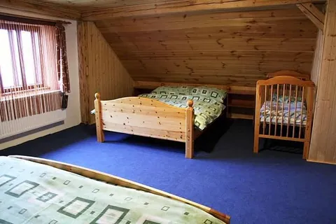 Podkrovní pokoj s postelí a dřevěnou dětskou postýlkou