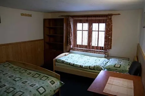Pokoj s dřevěným obkladem, postelemi a regálem