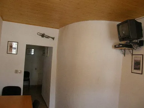 Světlá místnost s televizí na držáku a průchodem do chodby